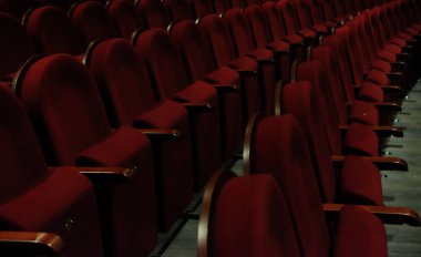 Kırmızı kadifeli numaralandırılmış tiyatro sandalyeleri.