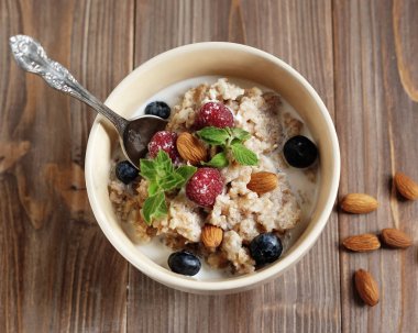 sağlıklı beslenme ve diyet kavramı: yulaf lapası kase tepesinde taze yaban mersini ve ahududu ahşap tablo