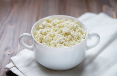 ahşap bir masa üzerinde bir kase taze peynir.