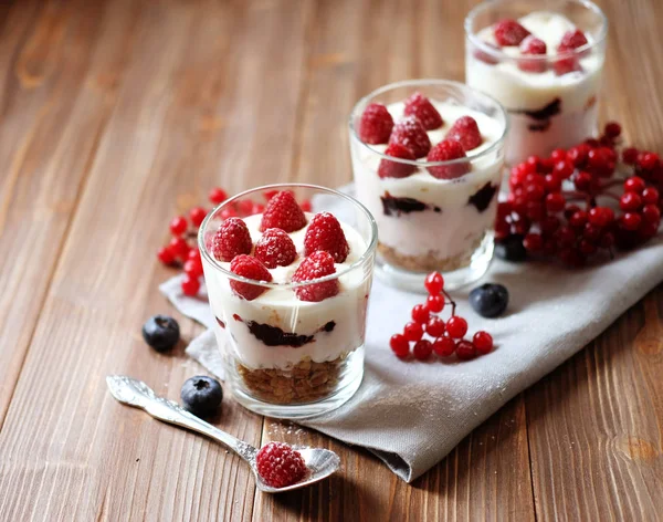 Hälsosam frukost - yoghurt med färska bär och müsli serveras i glasburk, på trä bakgrund — Stockfoto
