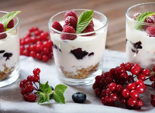 Terveellinen aamiainen - tuoreita marjoja ja mysliä sisältävä jogurtti lasipurkissa, puupohjalla — kuvapankkivalokuva