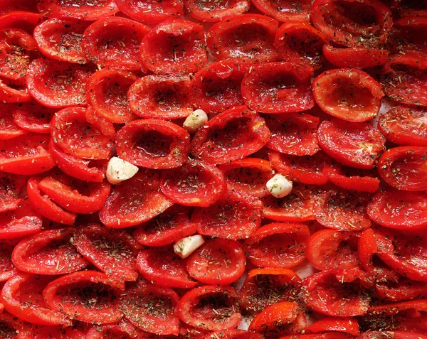 Domates bir fırın tepsisine pişirmeye hazır yalan. Kurutulmuş domates sarımsak ile. — Stok fotoğraf