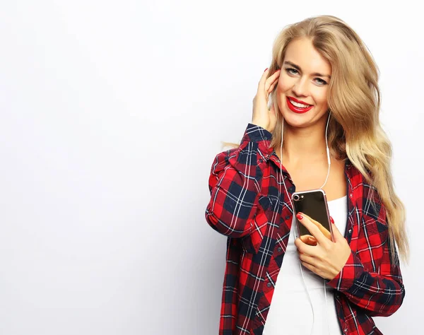 Glad ung kvinna lyssnar på musik från smartphone över vitt — Stockfoto