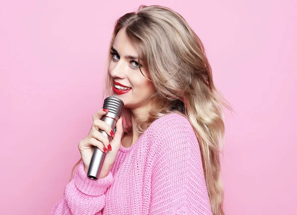 Lifestyle- und People-Konzept: Beauty-Model Sängerin mit Mikrofon vor rosa Hintergrund — Stockfoto