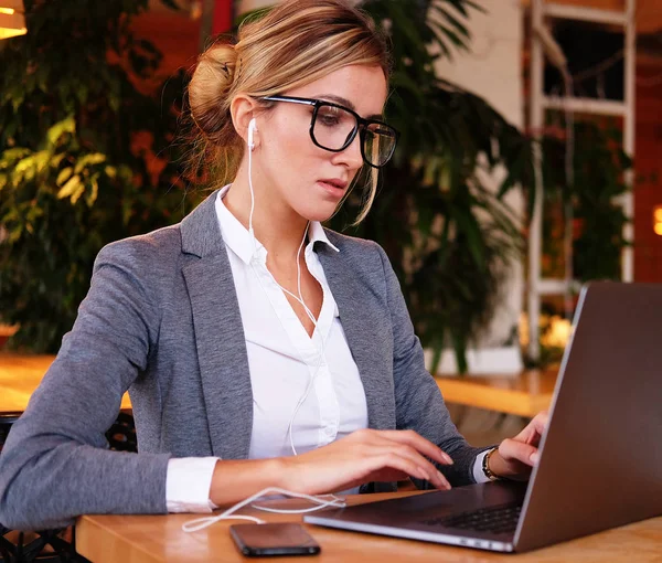 Üzleti wooman használ a laptop a kávézóban. Fiatal nő ül egy kávézóban, és dolgozik a számítógépen. Életmód és az üzleti koncepció. — Stock Fotó
