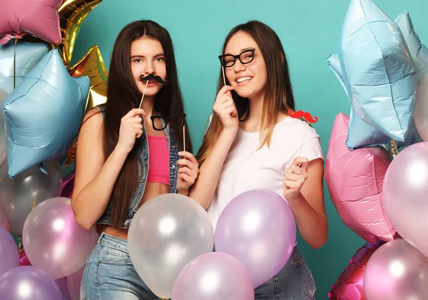 Gotowy na imprezę. Dwie dziewczyny w stylowym stroju letnim, papierowe okulary i balony powietrzne dobrze się bawią i świętują urodziny. — Zdjęcie stockowe