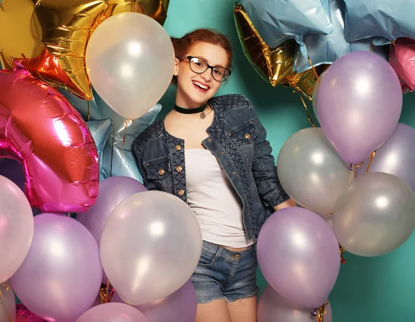 Glücklich Rothaarige Mädchen wartet auf Party. wunderschöne, fröhliche junge Frau, die Spaß mit funkelnden Luftballons vor blauem Hintergrund hat. Lifestylekonzept. — Stockfoto