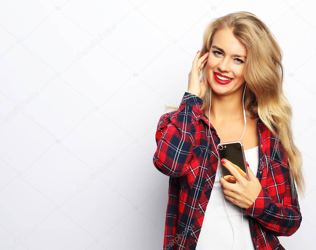 Happy young woman  listening to music from smartphone over white