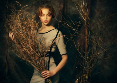 Güzellik ve sanat kavramı: kuru dalları ile parlak makyaj ile genç kadın