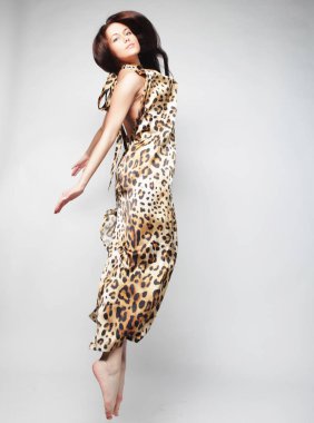 Genç sevimli kadın şifon elbise gri arka plan üzerinde atlama