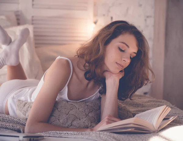 Estilo de vida y el concepto de la gente: mujer acostada en la cama mientras lee un libro — Foto de Stock