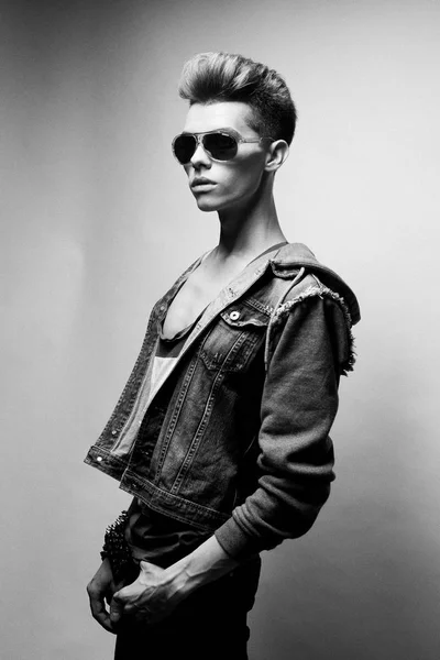 Gut aussehender junger Mann mit modischem Haarschnitt und Sonnenbrille posiert im Studio. Schwarz-Weiß-Bild. weißer Hintergrund. — Stockfoto