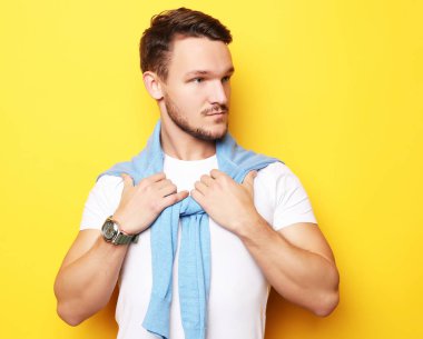 Yakışıklı bir gencin portresi, manken. Sarı duvarın üstünde poz veriyor. Yaşam tarzı ve moda konsepti.
