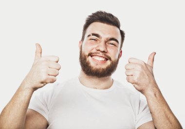 Beyaz arka planda izole edilmiş iyi bir hareket gösteren neşeli, sakallı genç bir adamın portresi.