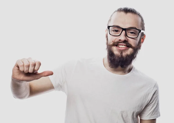 Atractivo joven con gafas apuntando a su camiseta blanca en blanco con el dedo índice, mostrando el espacio vacío para su texto publicitario o logotipo, statning aislado sobre fondo blanco . — Foto de Stock