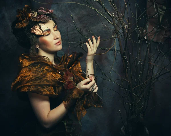 Concept beauté et art : Jeune femme au maquillage lumineux avec des branches sèches — Photo