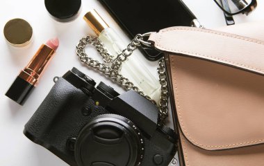 Kozmetik ürünleri, aksesuarlar, kamera ve beyaz arka planda akıllı telefonlu bej renkli kadın çantası. Güzellik ve moda konsepti.