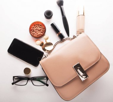 Düz pembe deri kadın çanta dışarı açık ile kozmetik, aksesuarlar, m-cüzdan ve smartphone beyaz arka plan üzerinde göklere.