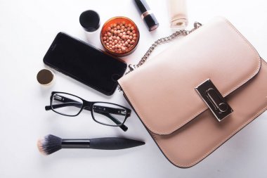 Düz pembe deri kadın çanta dışarı açık ile kozmetik, aksesuarlar, m-cüzdan ve smartphone beyaz arka plan üzerinde göklere.