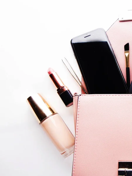 Flat lay of pink leather woman bag open out with cosmetics, accessories, wallet and smartphone on white background. Close up. — Stock Photo, Image