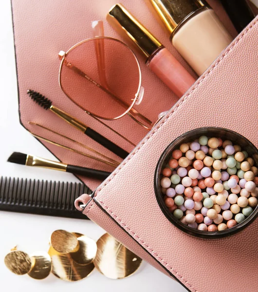 Concepto de moda y belleza: disposición plana de bolso de mujer de cuero rosa abierto con cosméticos y accesorios sobre fondo blanco. — Foto de Stock