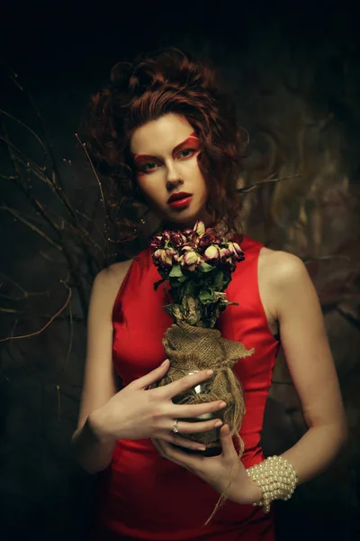 Beautiful stylish brunette in red dress holding a bouquet of dried flowers — Stock Photo, Image