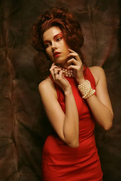 Όμορφη μελαχρινή με κόκκινο φόρεμα που ποζάρει σε θεατρικό φόντο — Φωτογραφία Αρχείου