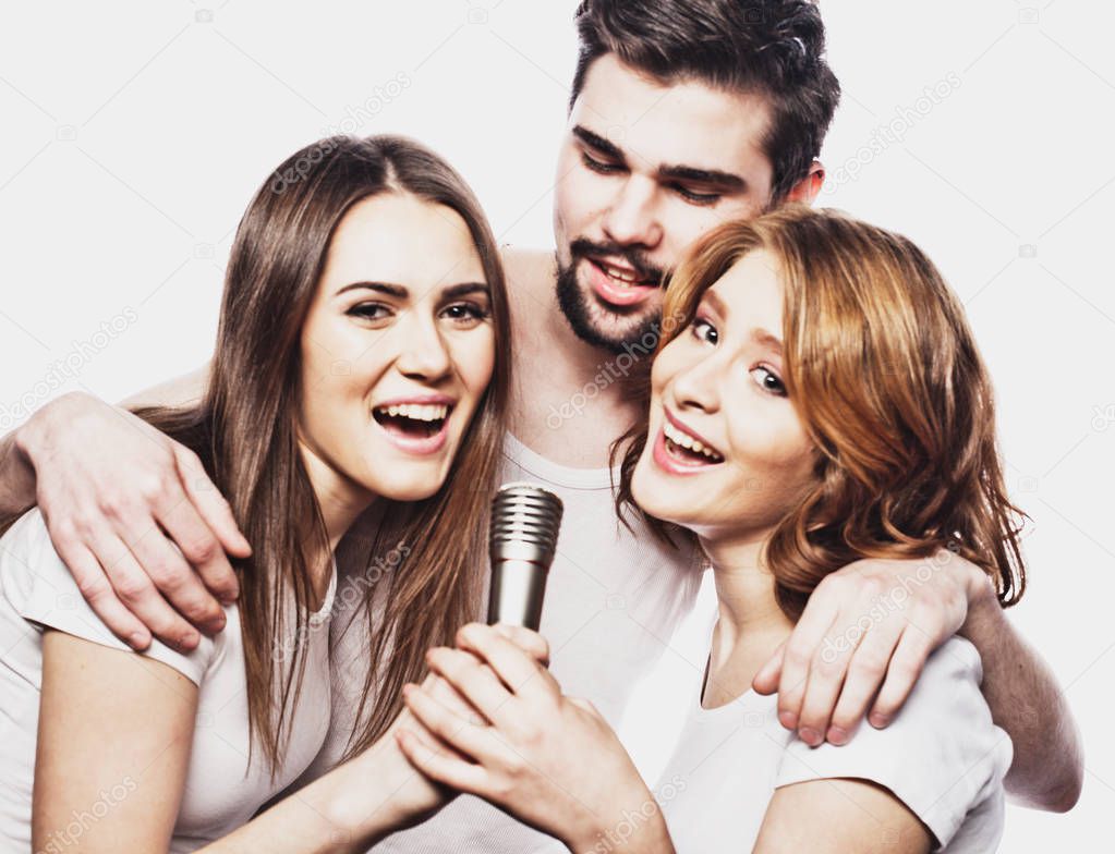 Portrait of happy girls and guys singing in microphone over white background.