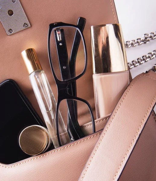 Düz pembe deri kadın çanta dışarı açık ile kozmetik, aksesuarlar, m-cüzdan ve smartphone beyaz arka plan üzerinde göklere.