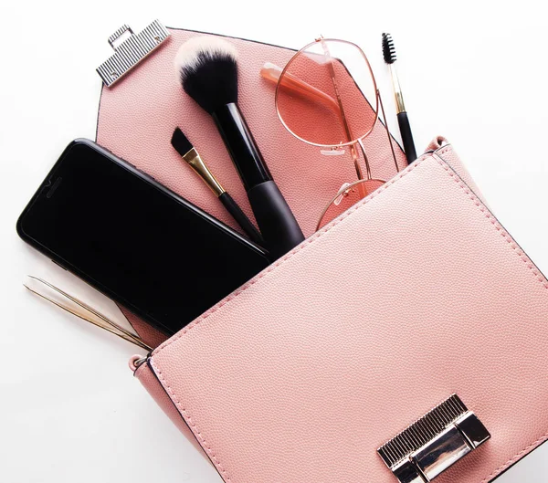 Concept mode et beauté : Pose plate de sac femme en cuir rose ouvert avec cosmétiques et accessoires — Photo