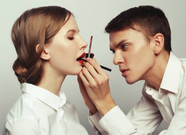 Makyöz, genç bir kadının profesyonel makyajını yapıyor.