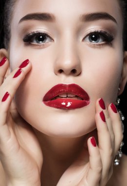 Kırmızı dudaklar ve çivi ile güzellik kız. Lüks kadın, takı küpe. Moda esmer siyah arka plan üzerine izole portre.