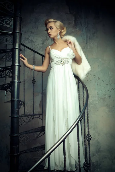 A fehér ruha gyönyörű fiatal menyasszony állva egy csigalépcsőn. Esküvői koncepció. — Stock Fotó