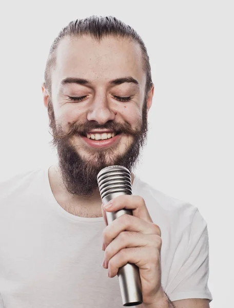 Çocuk sallanıyor. Mikrofona şarkı söyleyen sakallı yakışıklı bir adamın görüntüsü. Beyaz arka planda sakallı çekici bir adamın duygusal portresi. — Stok fotoğraf