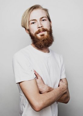 Yaşam tarzı ve insan konsepti: Genç sakallı adam beyaz arka planda kollarını kavuşturuyor