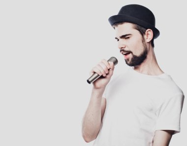 Genç adam mikrofonla şarkı söylüyor.