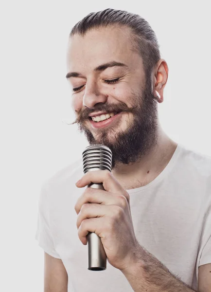 L'animateur. Jeune homme parlant tenant un microphone, isolé sur fond blanc. — Photo