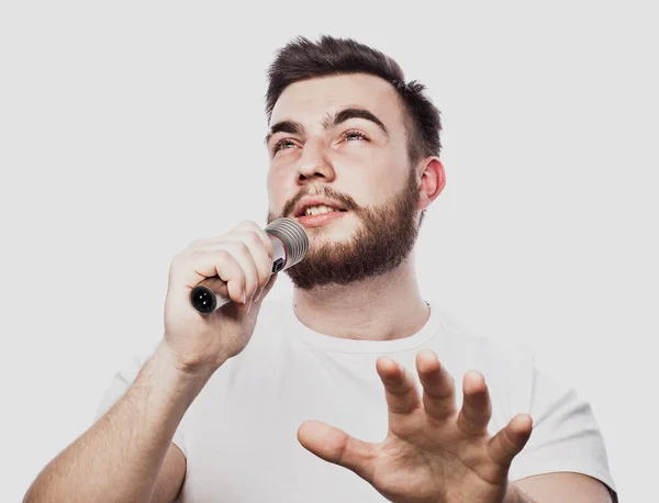 Sakallı adam mikrofon şarkı. Duygusal beyaz bir arka plan üzerinde sakallı çekici bir adam portresi — Stok fotoğraf