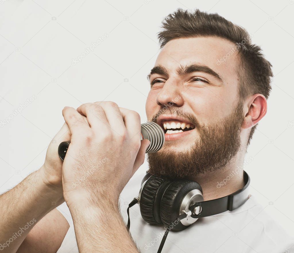 Young bearded man with headphones and microphone over white background