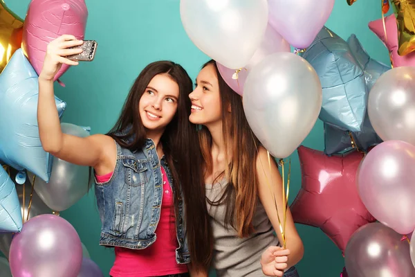 Dos amigas con globos de colores hacen selfie en un teléfono —  Fotos de Stock