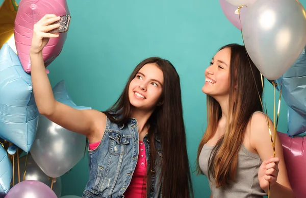 Dvě dívky s colorfoul balónky přátelě selfie na telefonu — Stock fotografie