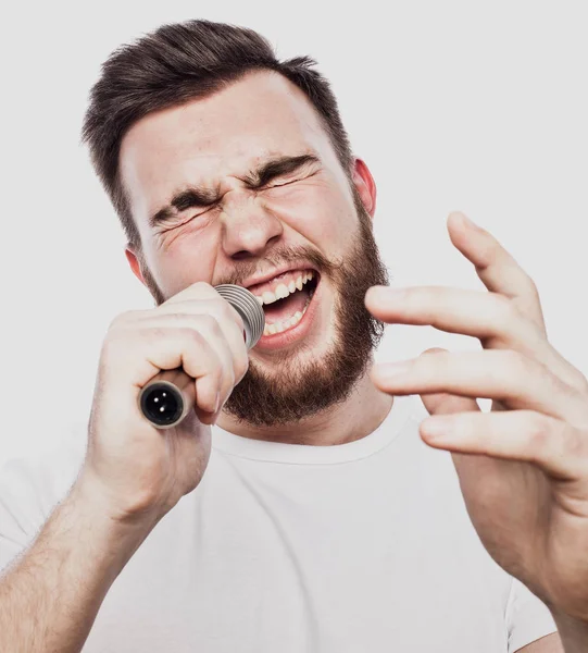 Boy Rocking Out. Image d'un bel homme barbu chantant au micro. Portrait émotionnel d'un homme séduisant avec une barbe sur fond blanc — Photo