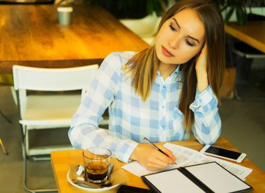 Zeki kadın fikirlerini yazıyor ve kafede kahve içiyor.