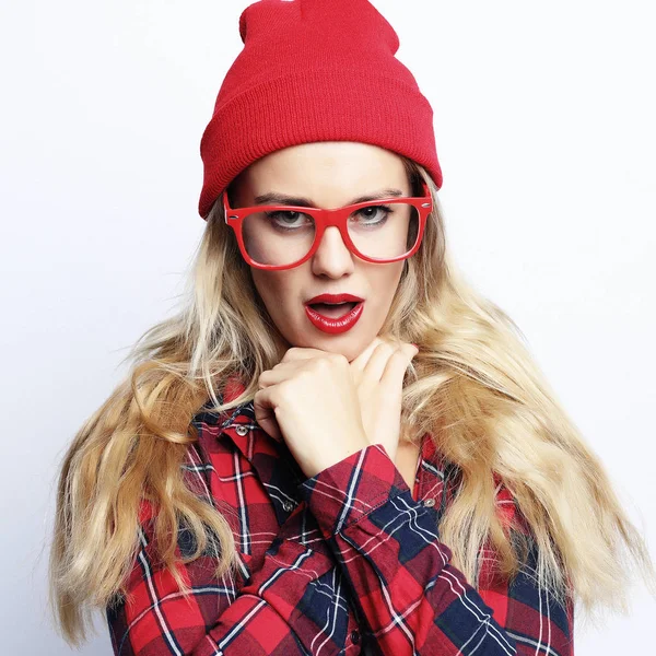 Retrato de estudio de moda de mujer rubia hipster bastante joven con maquillaje sexy brillante y gafas, con camisa a cuadros urbana con estilo y sombrero rojo — Foto de Stock