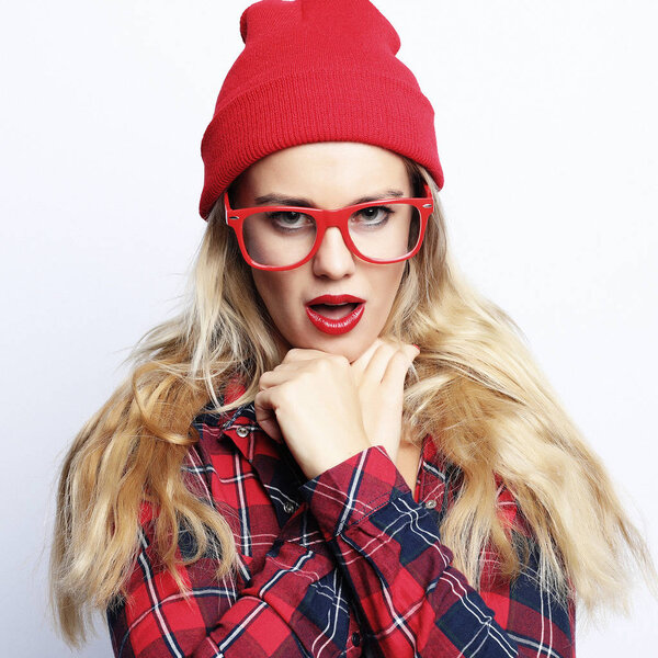 Fashion studio portrait of pretty young hipster blonde woman with bright sexy make up and glasses , wearing stylish urban plaid shirt and red hat