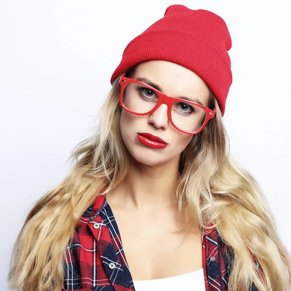 Μόδα στούντιο πορτρέτο του όμορφη νεαρή hipster ξανθιά γυναίκα με φωτεινά σέξι συνθέτουν και γυαλιά, φορώντας μοντέρνο αστικό καρό πουκάμισο και κόκκινο καπέλο — Φωτογραφία Αρχείου