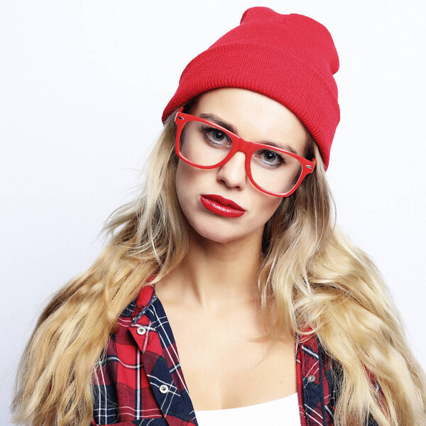 Fashion studio portrait of pretty young hipster blonde woman with bright sexy make up and glasses , wearing stylish urban plaid shirt and red hat