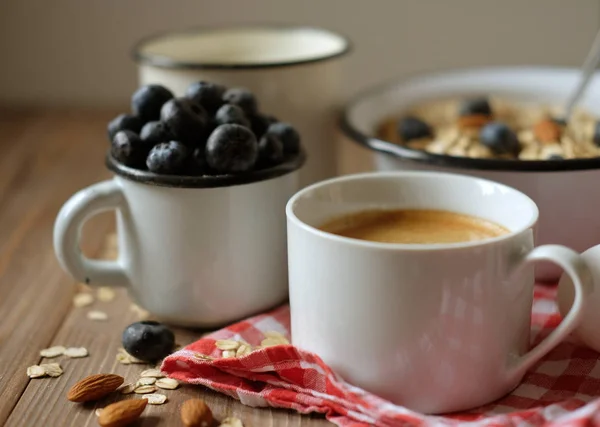 En hälsosam frukost är en bra start till en ny dag. Havregryn gröt, kaffe, bär och nötter på ett träbord. — Stockfoto