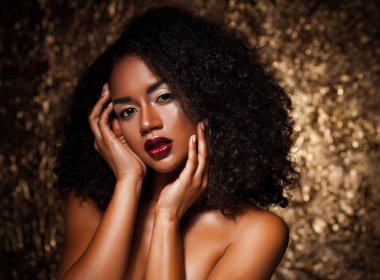 afro saçlı genç zarif Afrikalı-Amerikalı kadın. Glamour makyaj. Altın arka plan. 