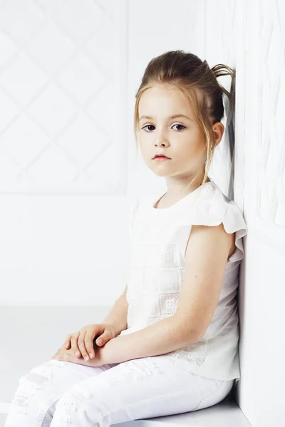 Childrens fashion. Beautiful pensive serious blonde girl in white clothes. Fashion, lifestyle and people concept. — Stock Photo, Image